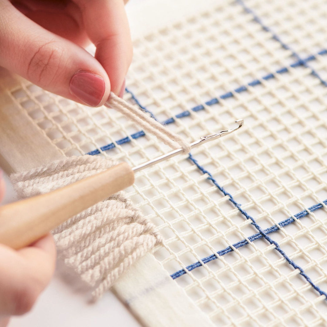 Latch hook in use, pulling yarn through canvas